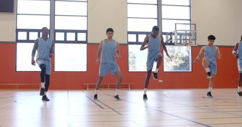 Diverse Male Basketball Team Doing Warmup Drills in Gym