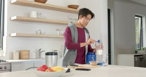 Man preparing protein shake in modern minimalist kitchen