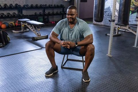 African american man resting on low plyo box after intense gym workout