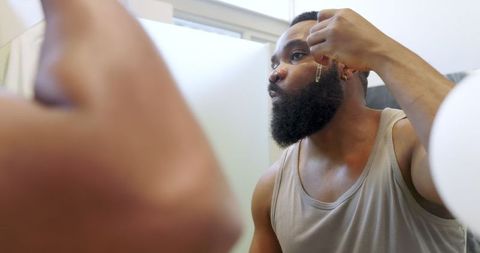 Man practicing self-care with beard oil in minimalist bathroom
