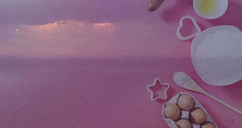 Baking supplies on pink surface overlooking tranquil seascape