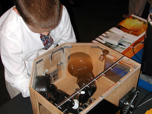 A young student actively participating in an educational event by demonstrating the use of a Middeck Glovebox, a mockup used for research in space shuttles. This image highlights the hands-on learning activities in space research conducted during the Space Research and You event, organized by NASA's Office of Biological and Physical Research, June 25, 2002, in Arlington, Virginia. It could be used in educational articles, presentations, and websites emphasizing the importance of engaging youth in science and technology, or to showcase NASA's programs and community outreach efforts.