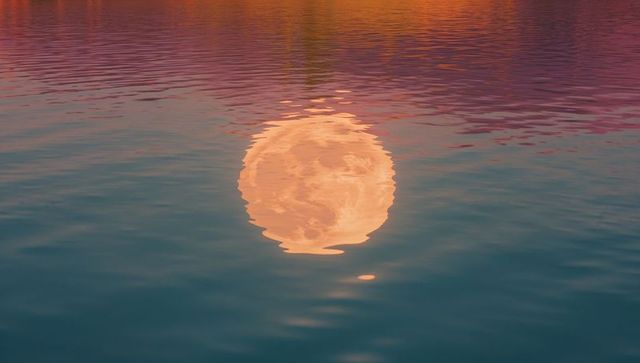 Moon reflection over rippling water during dusk
