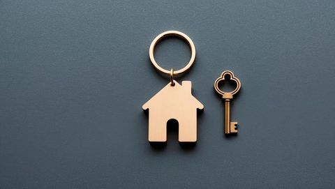 Minimalist house keychain with vintage key on gray surface