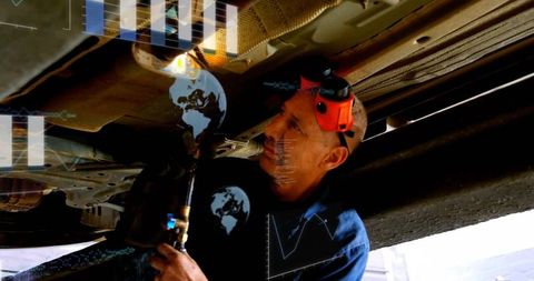 Mechanic repairing vehicle undercarriage with torch and hud diagnostics overlays