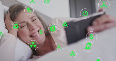 Senior Woman Relaxing in Bedroom While Using Eco-Friendly Technology on Tablet