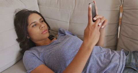 Young Woman Texting on Phone While Relaxing on Couch