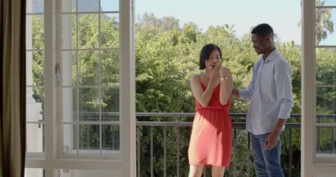 Joyful engagement proposal on scenic balcony