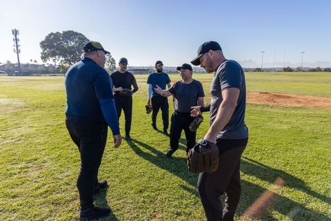Recreational baseball team gathering on sunny field planning strategy and warmup