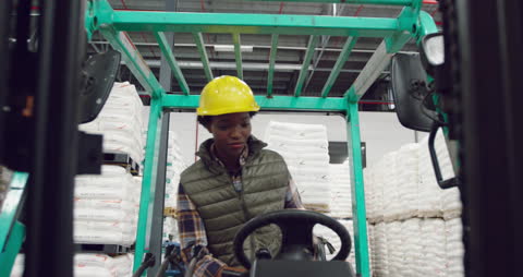 Warehouse Worker Climbing onto Forklift while Talking on Smartphone