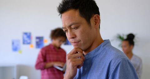 Thoughtful Asian Manager Analyzes Data on Tablet in Modern Workspace