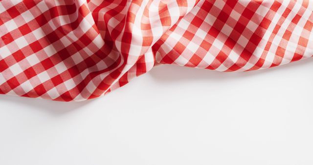Close up of red and white checkered blanket on white background with copy space. Picnic day, food and nature concept.