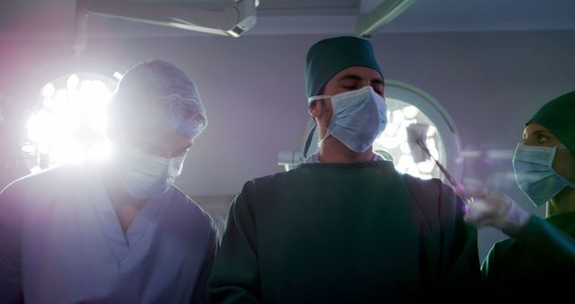 A diverse team of surgeons, including Caucasian and Asian individuals, is focused on a procedure in a brightly lit operating room, with copy space. Their intense concentration and professional attire underscore the critical nature of surgical operations.
