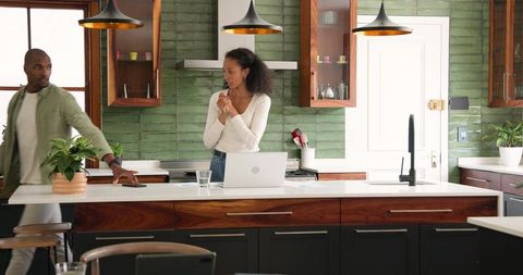 Woman in Modern Kitchen with Laptop Surprise and Thought