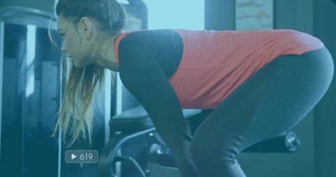 Young athletic woman performing bent-over row at modern gym