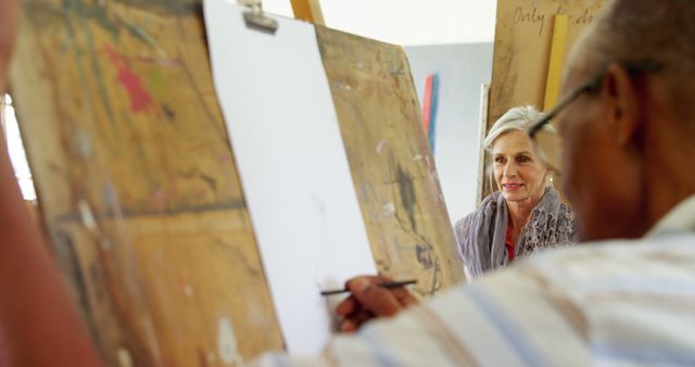 Senior adults enthusiastically participating in an art class drawing on canvases. Perfect for content promoting senior activities, creative workshops for elderly, educational programs for older adults, and theme of lifelong learning.