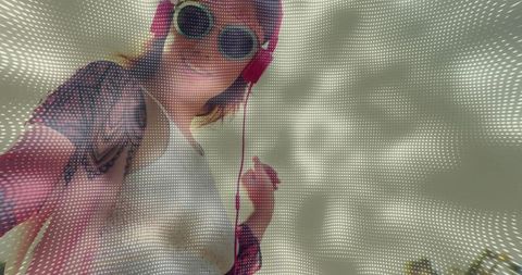 Tilting woman wearing pink headphones, sunglasses, raising hand with dotted halftone overlay