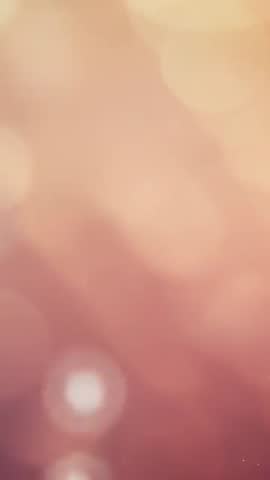 Vertical bokeh background video featuring warm amber glow and drifting soft orbs for overlays