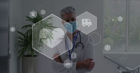Senior physician standing arms crossed wearing mask and stethoscope with vitals hex overlay