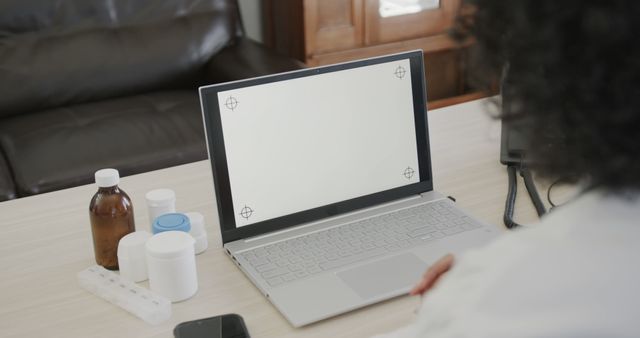 Person Using Laptop at Desk with Medicines and Phone - Download Free Stock Images Pikwizard.com