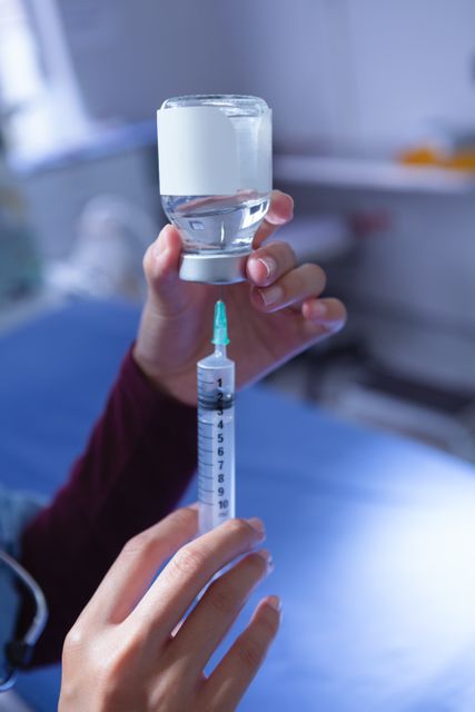 This image shows a close-up of a female surgeon filling a syringe with medicine from an ampule in a hospital operation room. It can be used for healthcare, medical, and hospital-related content, including articles, blogs, and educational materials about medical procedures, vaccinations, and healthcare professionals.