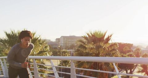 Man Jogging on Bridge with Wireless Earphones at Sunrise