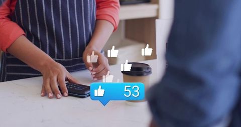 Barista tapping contactless card reader at cafe counter with social media like icons