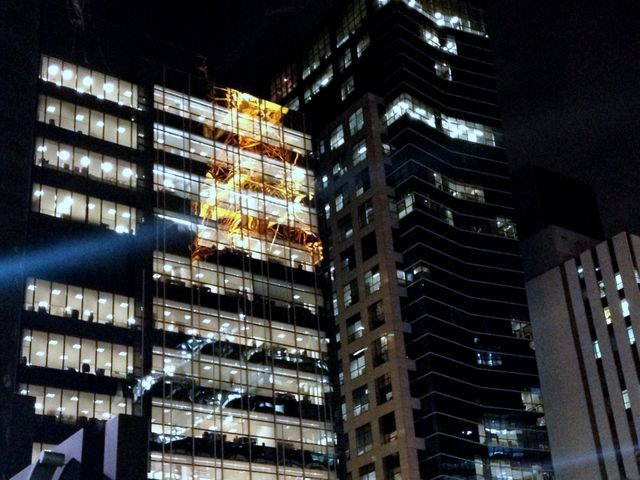 Night view of high-rise office buildings with illuminated windows contrasting against the dark sky. Great for usage in themes related to corporate environment, modern urban life, business presentations, architecture projects, and city life dynamics.