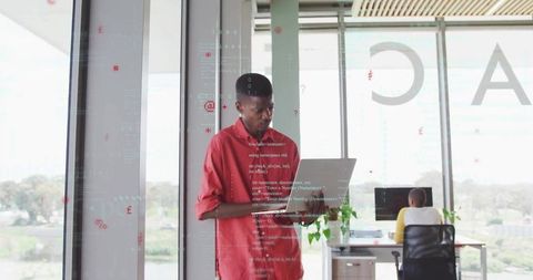 Man Engaged in Coding with Laptop in Modern Office Space