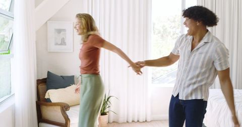 Happy Couple Holding Hands in Bright Bedroom Interior