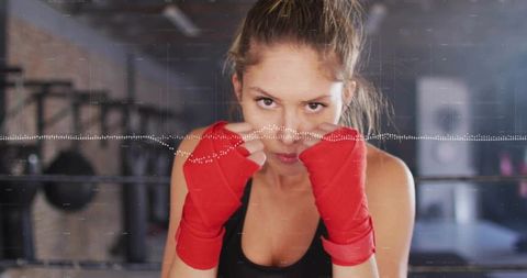 Female boxer holding guard with red hand wraps in gym with dotted waveform overlay