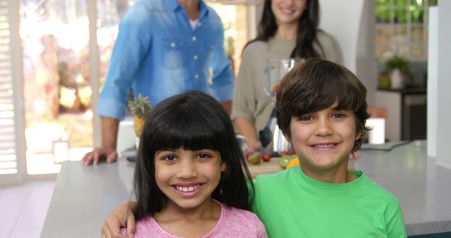 Smiling Siblings in Modern Kitchen with Parents in Background - Download Free Stock Images Pikwizard.com