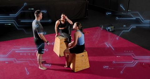 Trainer coaching two women on plyo boxes with futuristic digital overlay in gym studio