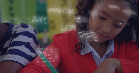 Schoolgirl wearing red sweater writing at desk focusing on homework with green pencil