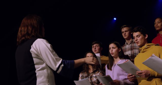 Choir director conducting group of young singers on stage during rehearsal - Download Free Stock Images Pikwizard.com