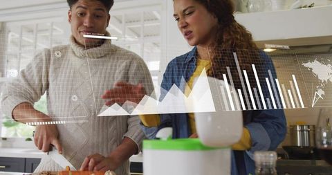 Couple chopping vegetables with smart blender and financial charts overlay in kitchen