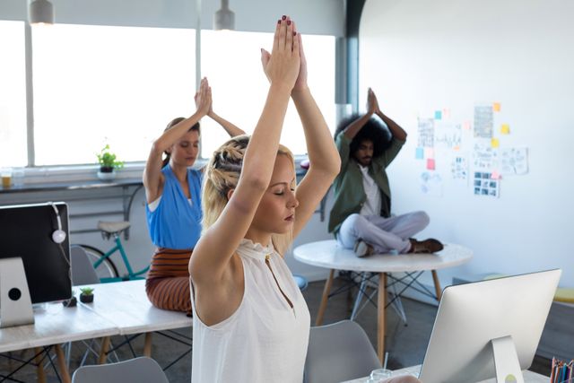 Office workers practicing yoga at their desks, promoting workplace wellness and stress relief. Ideal for illustrating corporate wellness programs, employee health initiatives, and mindfulness in the workplace. Useful for articles on productivity, work-life balance, and healthy office environments.
