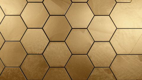 Luxurious hexagonal gold honeycomb tiles with brushed metallic texture and dark seams