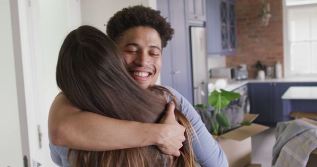 Happy biracial couple moving house, embracing and smiling in kitchen. quality time, relaxing together at home.