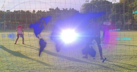 Goalkeeper defending with world map lens flare overlay on sunlit soccer field