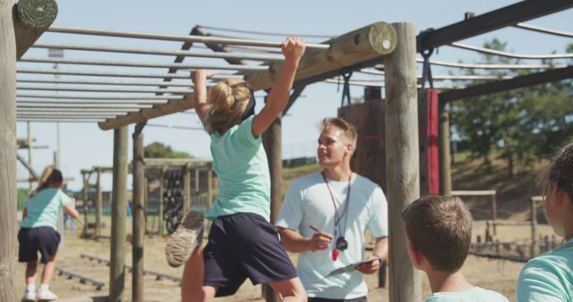Children are participating in a physical education class and practicing on monkey bars. A teacher or trainer monitors their progress and provides guidance. This type of activity promotes fitness, teamwork, and outdoor fun. Can be used for articles and materials related to childhood fitness, school activities, physical education programs, and child development.