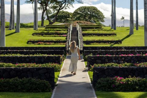 Woman Walking Through Tropical Garden Path with Stone Walls