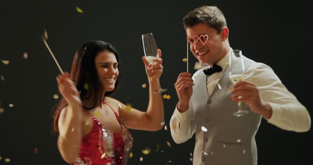 Caucasian couple celebrating with champagne, with copy space. They're enjoying a festive moment with confetti in the air.
