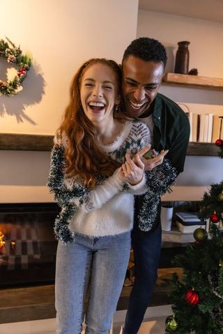 Diverse couple embracing in festive holiday living room