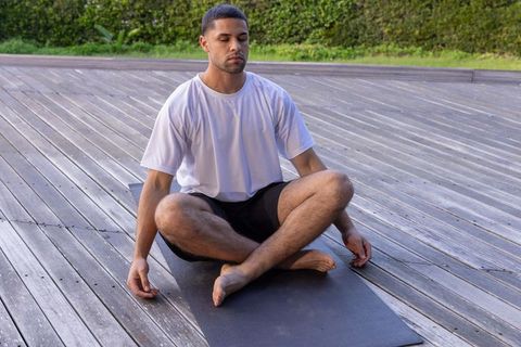 Man Meditating Peacefully Outdoors on Wooden Deck