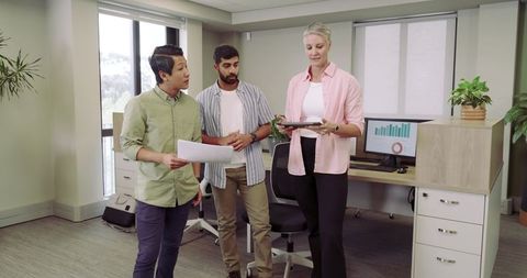 Diverse Team Collaborating in Modern Office with Tablet and Printout