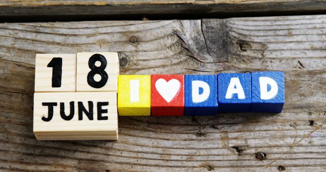 Wooden block calendar displaying date June 18 alongside colorful blocks spelling 'I ? DAD' on rustic wood surface. Perfect for use in Father's Day greeting cards, holiday marketing materials, promotional items, social media posts, and family celebration invitations.