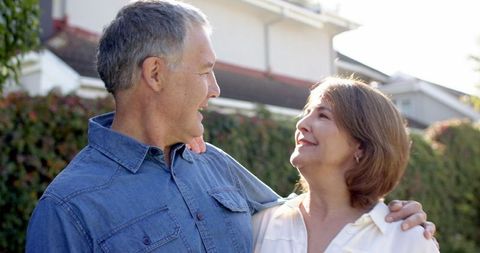 Senior Couple Embracing in Sunny Backyard Sharing Joyful Glances