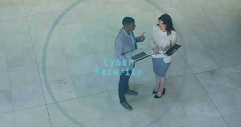 Discussing cyber security strategy in corporate atrium with laptop and folder projection