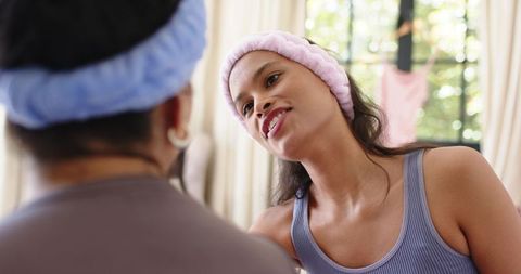 Young woman leaning in sharing intimate conversation with companion wearing headbands
